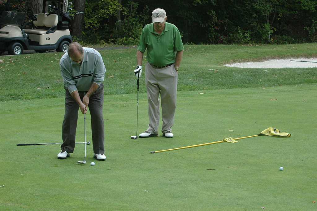 Two golfers putting at a US Army Tournament to support local schools
